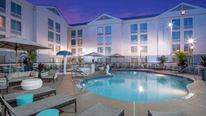 Un hotel con piscina, mobiliario exterior y un patio cubierto.