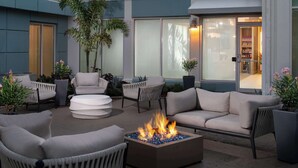 Un patio con mobiliario exterior, una fogata y plantas en macetas.