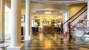 A hotel lobby with a checkered floor, a grand staircase, and a chandelier. - The Marshall House, Historic Inns of Savannah (Savannah)