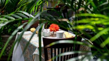 Uma mesa posta com toalha estampada, um vaso com flores laranjas e um guardanapo amarelo.