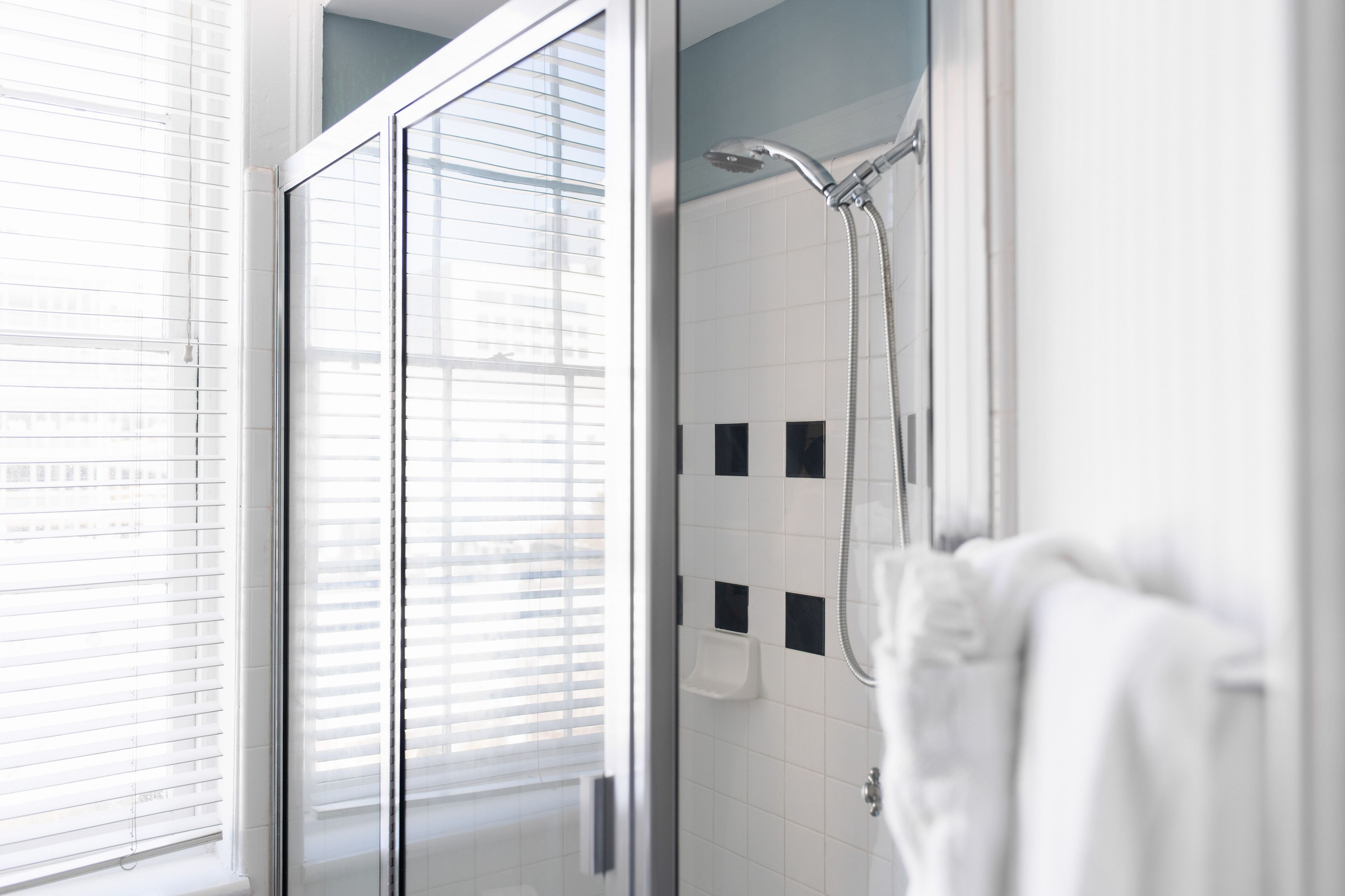Un baño moderno con cabina de ducha de vidrio, azulejos blancos y un perchero para toallas.