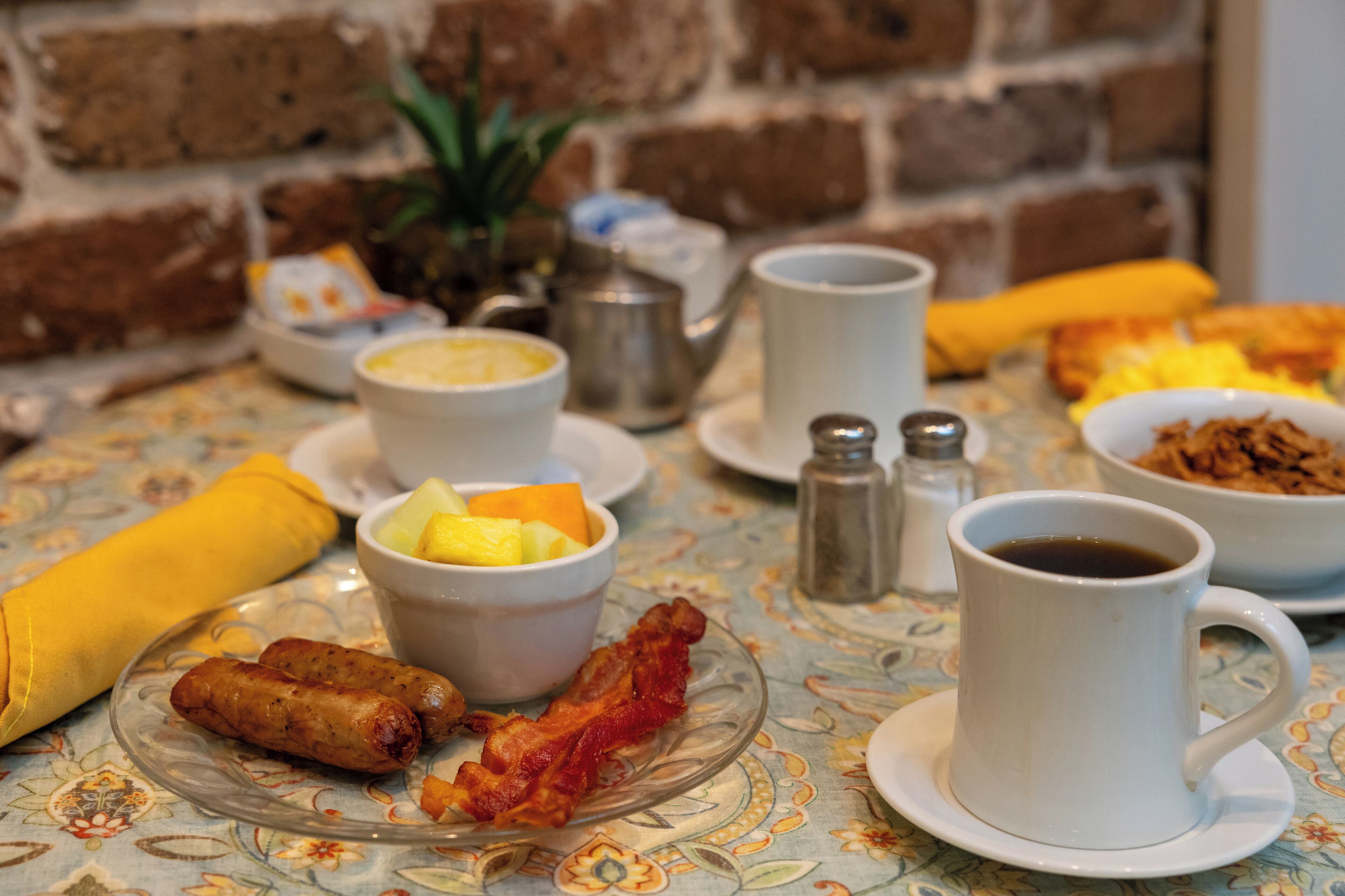 Une table de petit-déjeuner avec divers plats, notamment des œufs, du bacon et des fruits.