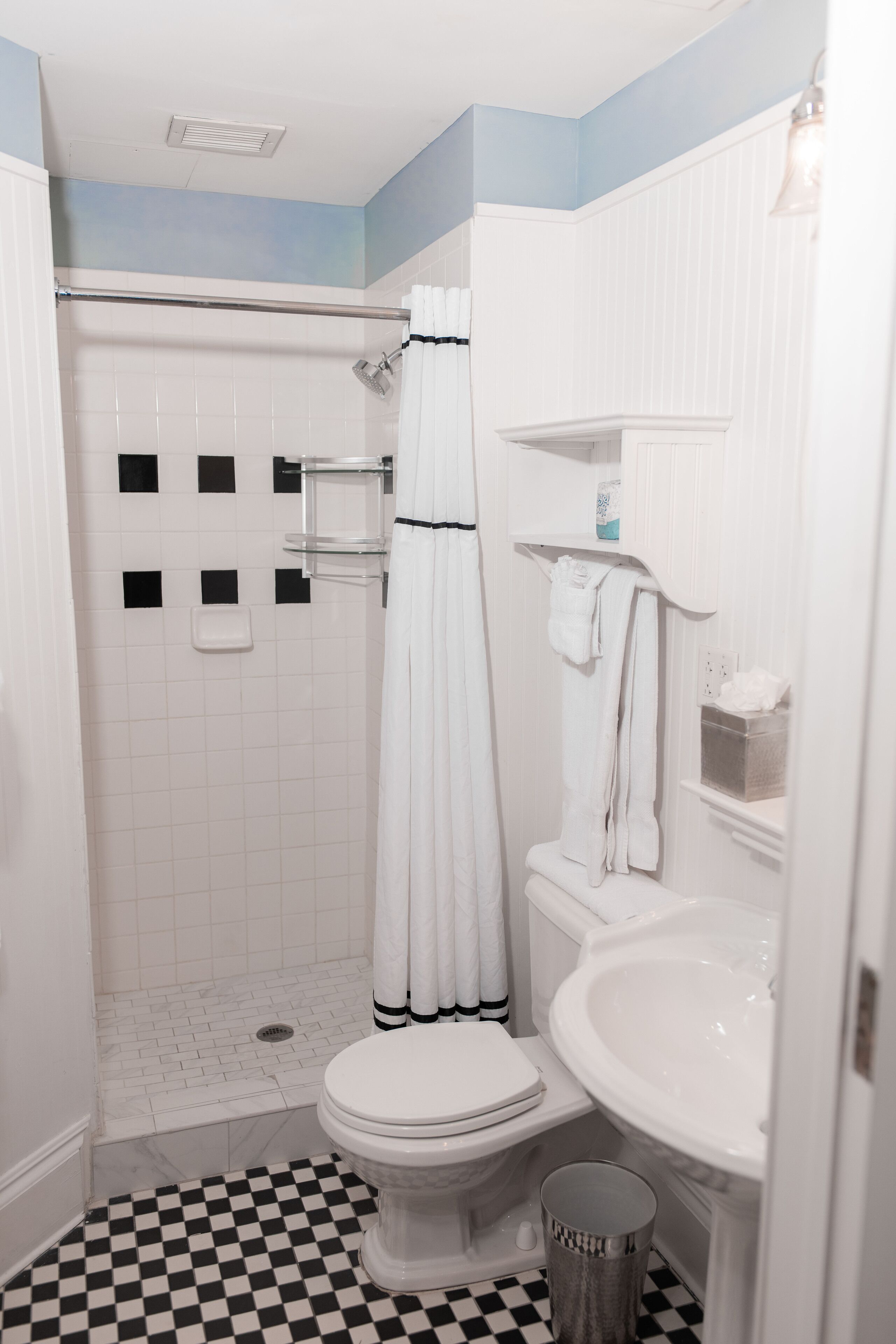 A bathroom with a white toilet, a sink, and a shower.