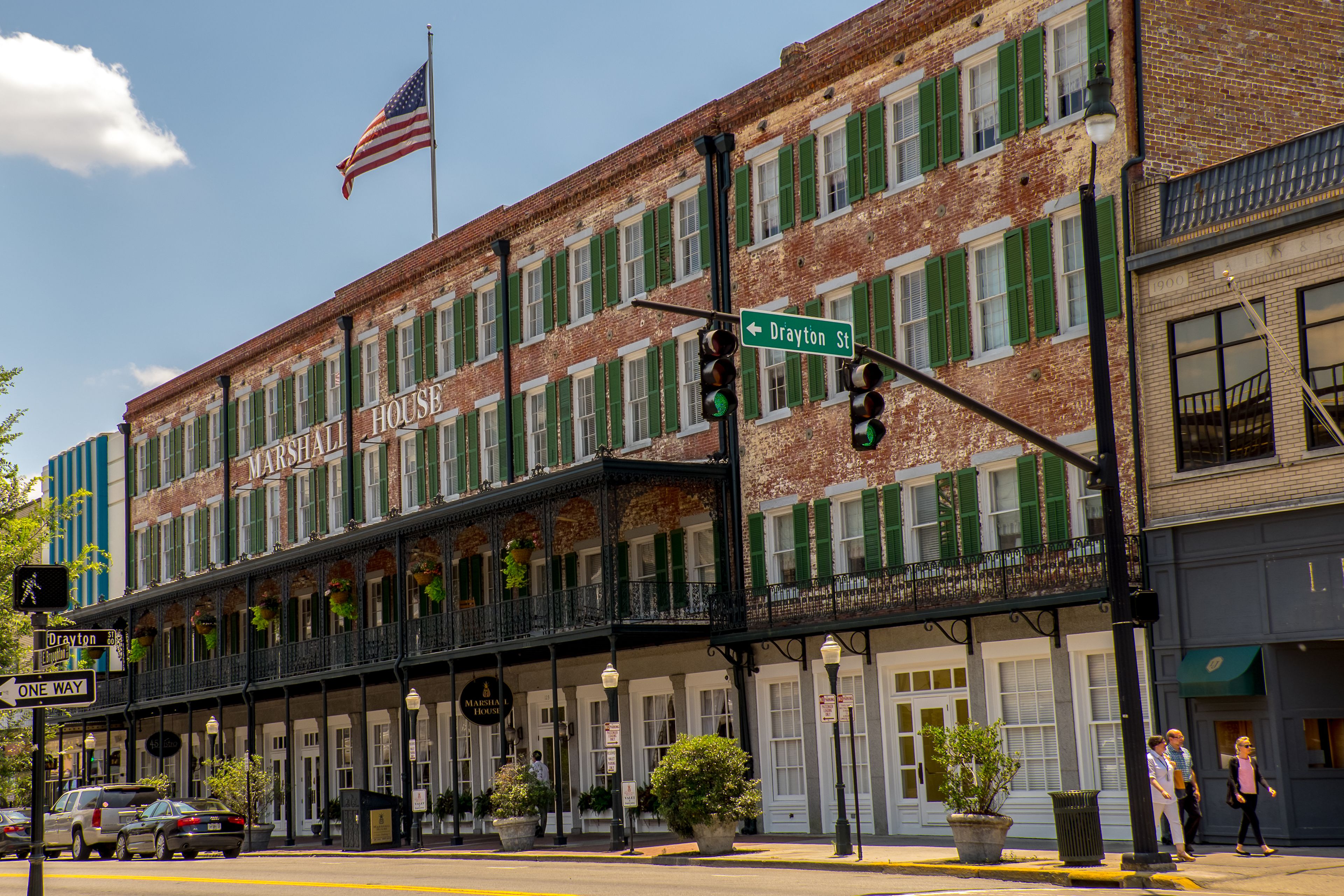 A historic building with a balcony, a sign for 'Drayton St', and an American flag.