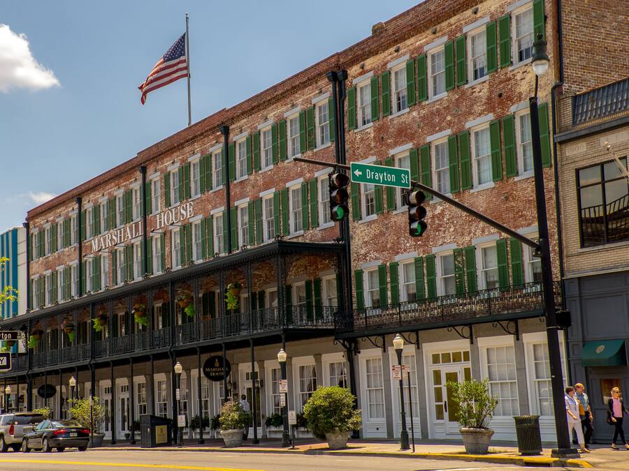 A historic building with a balcony, a sign for 'Drayton St', and an American flag.