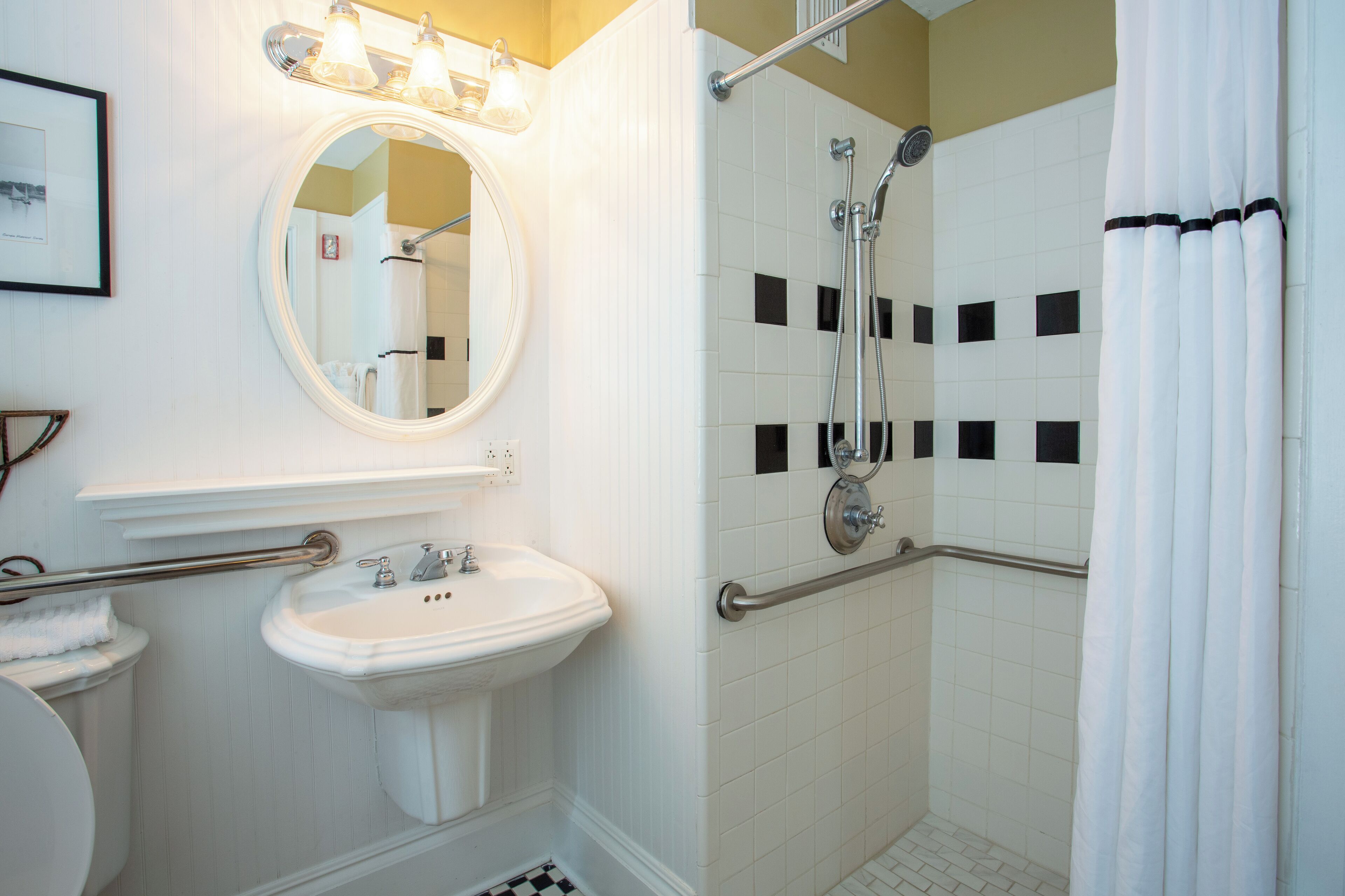 A bathroom with a white sink, mirror, and shower.