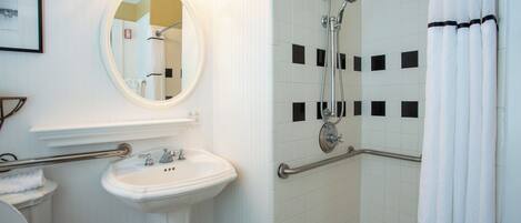A bathroom with a white sink, mirror, and shower.