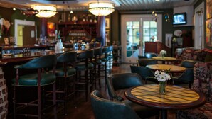 A bar area with multiple seating options, including bar stools and round tables with floral centerpieces. - The Marshall House, Historic Inns of Savannah (Savannah)