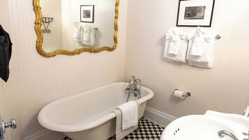 A bathroom with a freestanding bathtub, a sink, a mirror with a gold frame, and towels hanging on a rack.