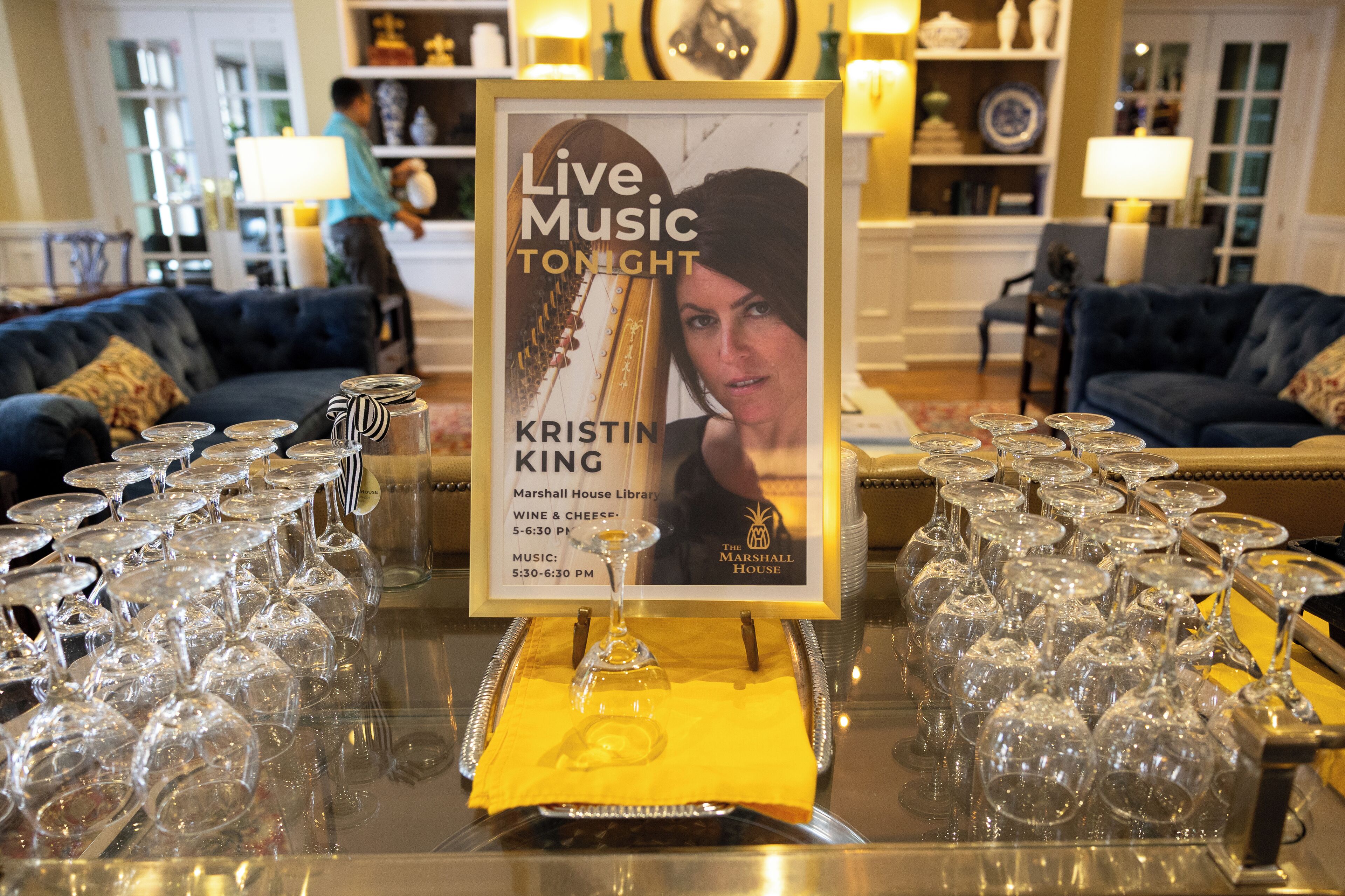 A framed poster advertising a live music event with a wine and cheese reception.