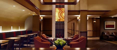A hotel lobby with a central seating area, a fireplace, and a modern design.