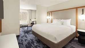 A hotel room with a large bed, a desk, and a chair.