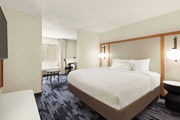A hotel room with a large bed, a desk, and a chair.