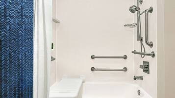 A modern bathroom with a shower, grab bars, and a white bathtub.