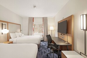 A hotel room with two beds, a desk, a chair, a TV, and a window with curtains.