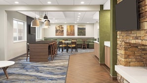 A modern dining area with a stone accent wall, a flat-screen TV, and a blue patterned carpet.