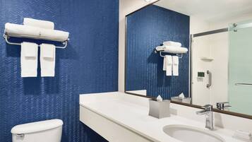 Un baño moderno con pared azul estampada, un lavamanos blanco y un inodoro.