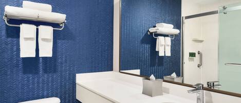 Un baño moderno con pared azul estampada, un lavamanos blanco y un inodoro.