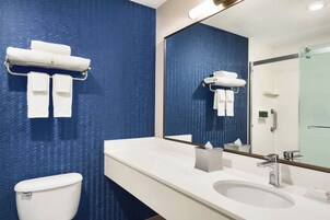 Un baño moderno con pared azul estampada, un lavamanos blanco y un inodoro.