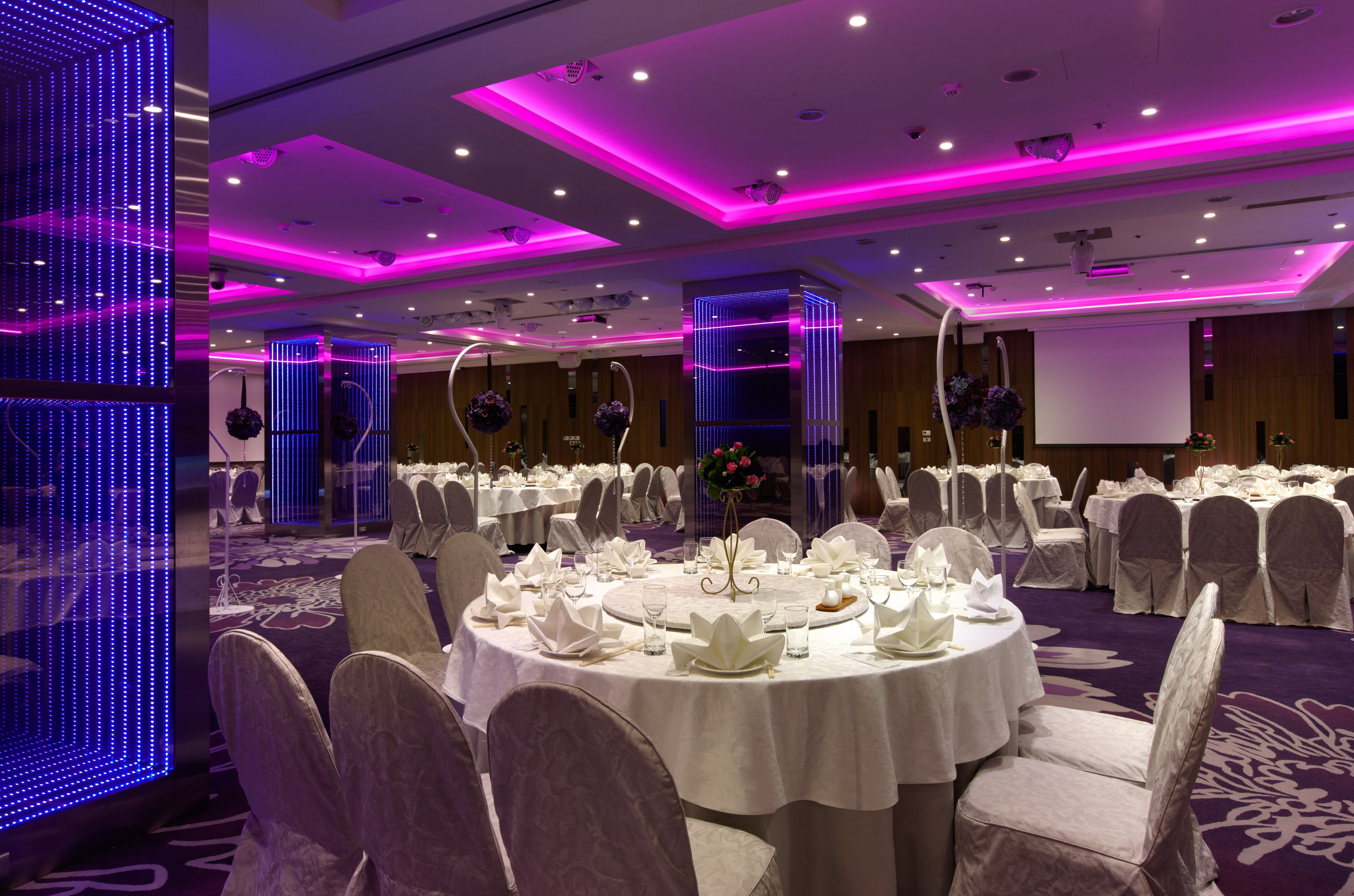 A banquet hall with round tables set for a formal event, featuring white tablecloths and chairs.