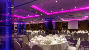 A banquet hall with round tables set for a formal event, featuring white tablecloths and chairs.