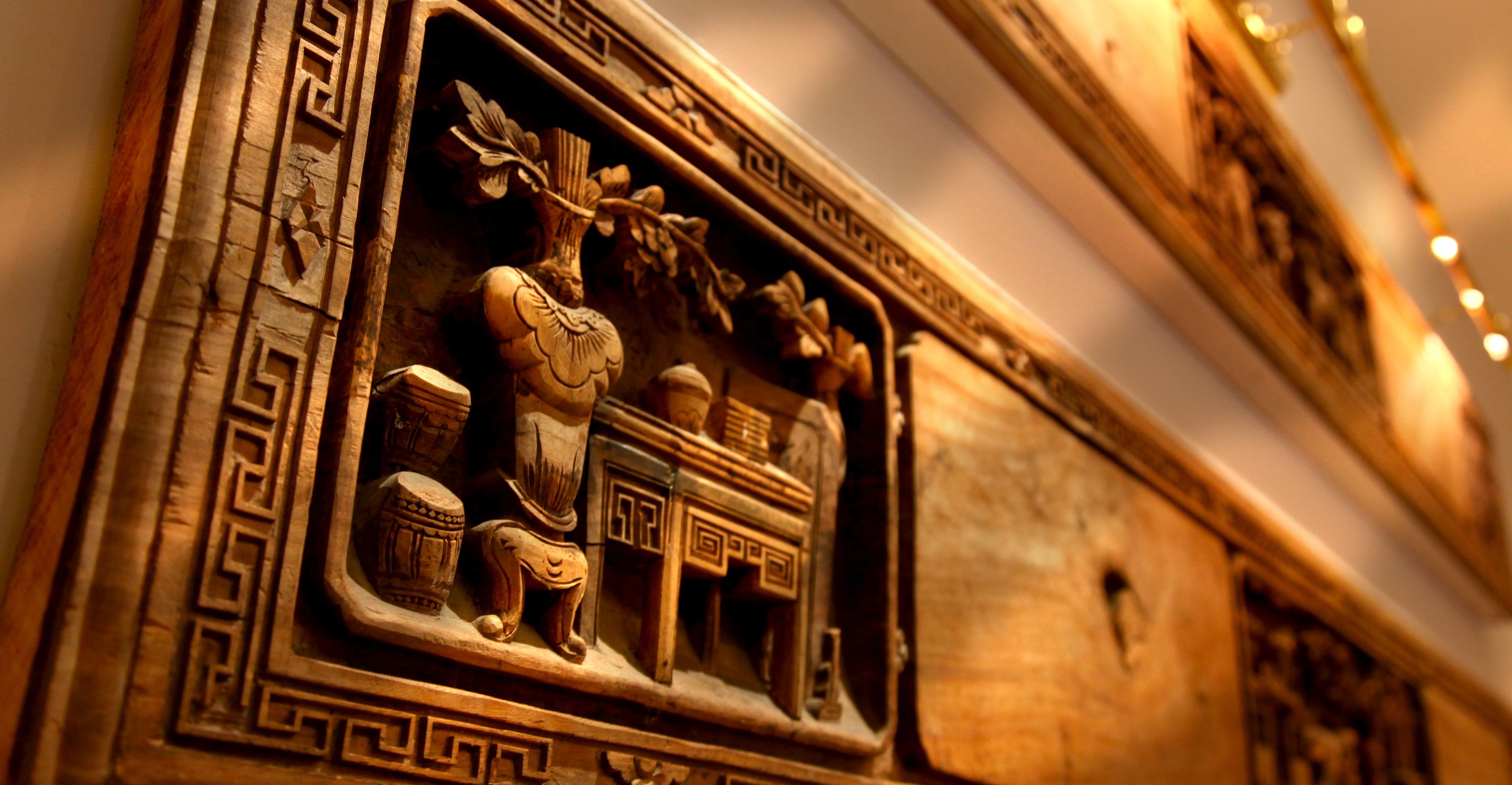 A detailed architectural carving with geometric patterns and classical figures.