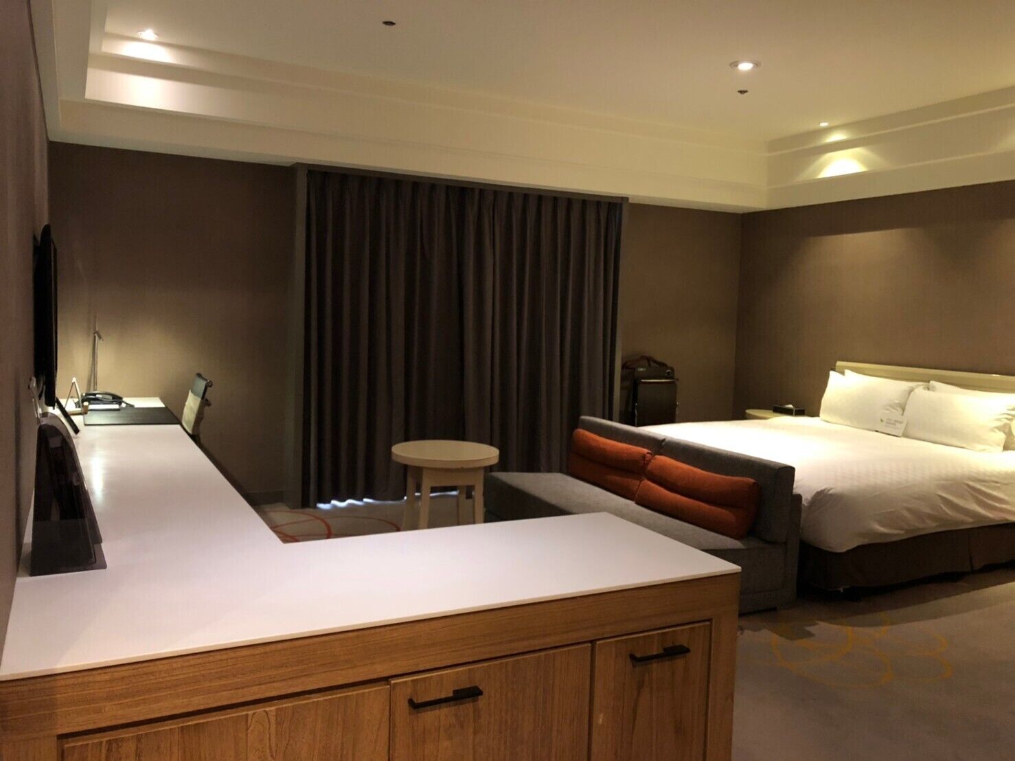 Une chambre d’hôtel comprenant un lit, un bureau, une chaise, une petite table et une armoire.