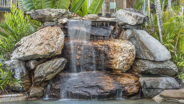 Una cascata che si getta su grosse rocce in un giardino.