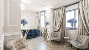 A spacious living room with a herringbone floor, a blue sofa, and two armchairs. - FH55 Hotel Calzaiuoli (Florence)