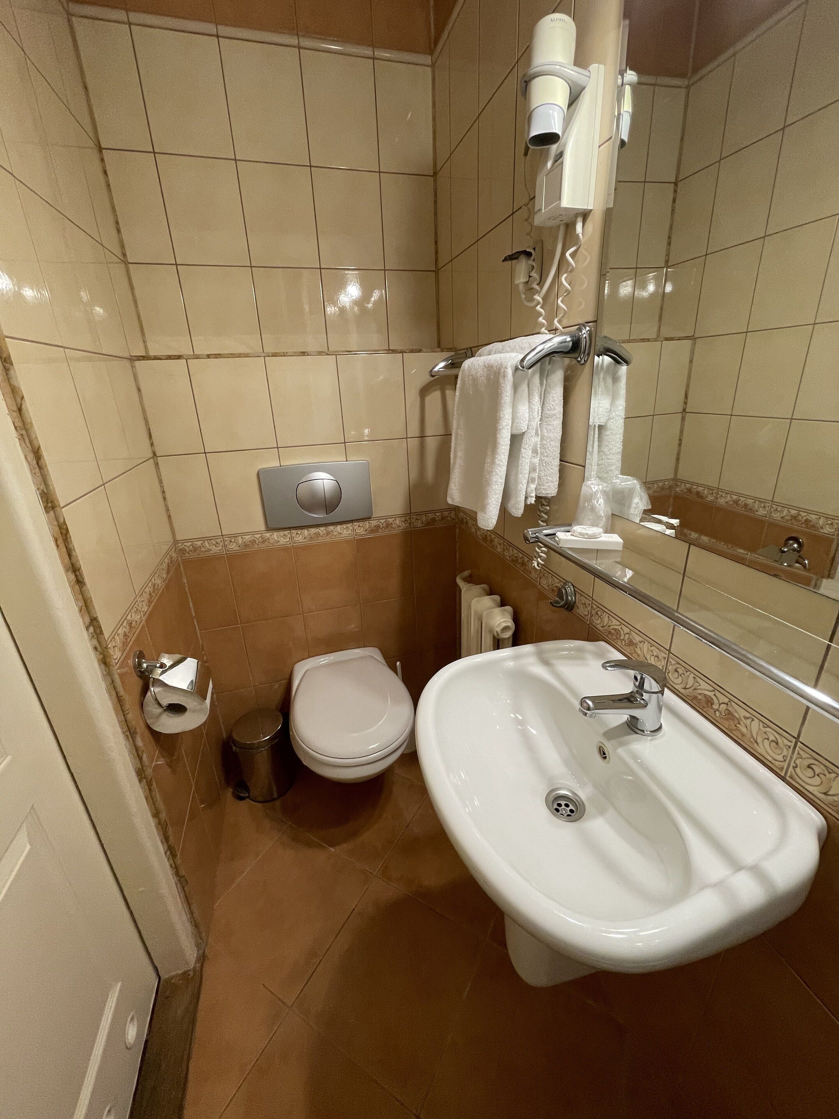 Ein kleines Badezimmer mit Toilette, Waschbecken und Handtuchhalter.