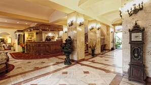 A lobby with a reception desk, a large clock, and a fountain. - Hotel Europejski (Kraków)