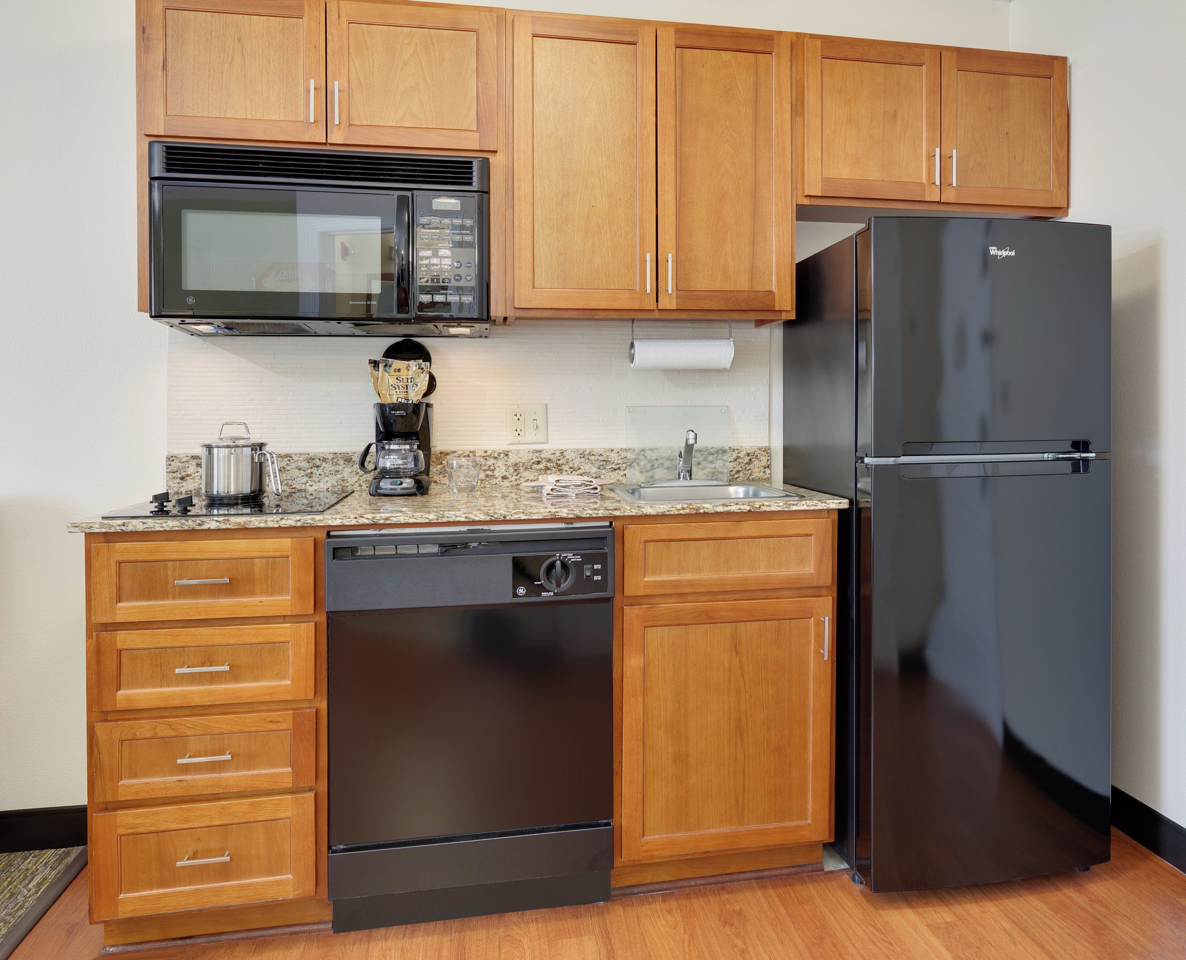 A kitchen with wooden cabinets, a microwave, a refrigerator, a dishwasher, and a coffee maker.