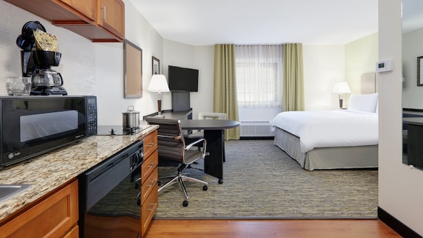Una habitación de hotel con kitchenette, una cama, un escritorio y televisor.