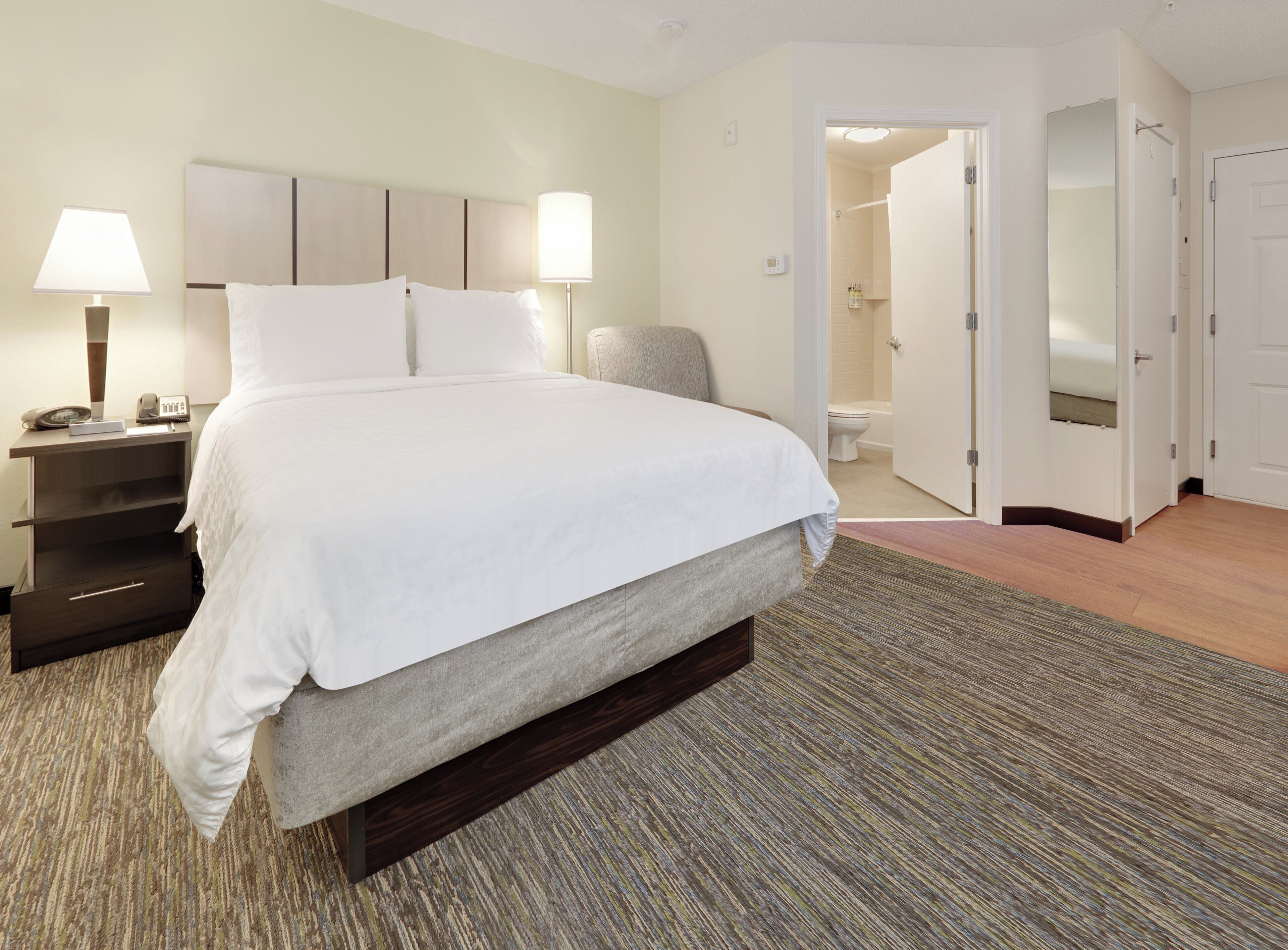 A hotel room with a large bed, bedside lamps, a nightstand, and a view of the bathroom.