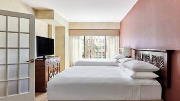 Een hotelkamer met twee bedden, een televisie, een bureau en een raam met gordijnen.