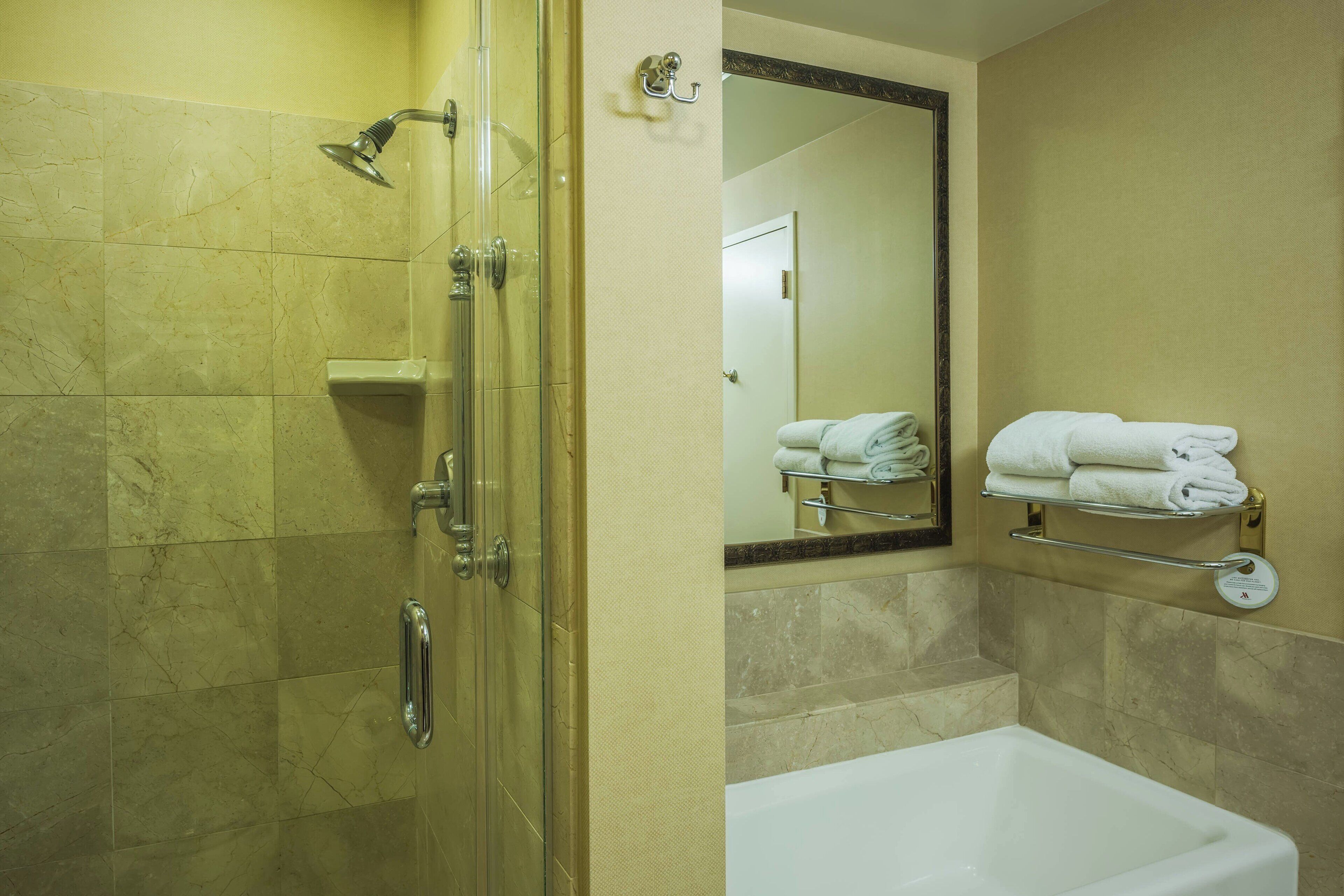 Un bagno con doccia vetrata, una vasca da bagno bianca e un portascopevoli con asciugamani piegati.