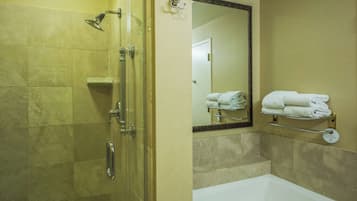 Un bagno con doccia vetrata, una vasca da bagno bianca e un portascopevoli con asciugamani piegati.