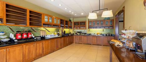 A spacious kitchen with wooden cabinets, a long counter, and a coffee station.