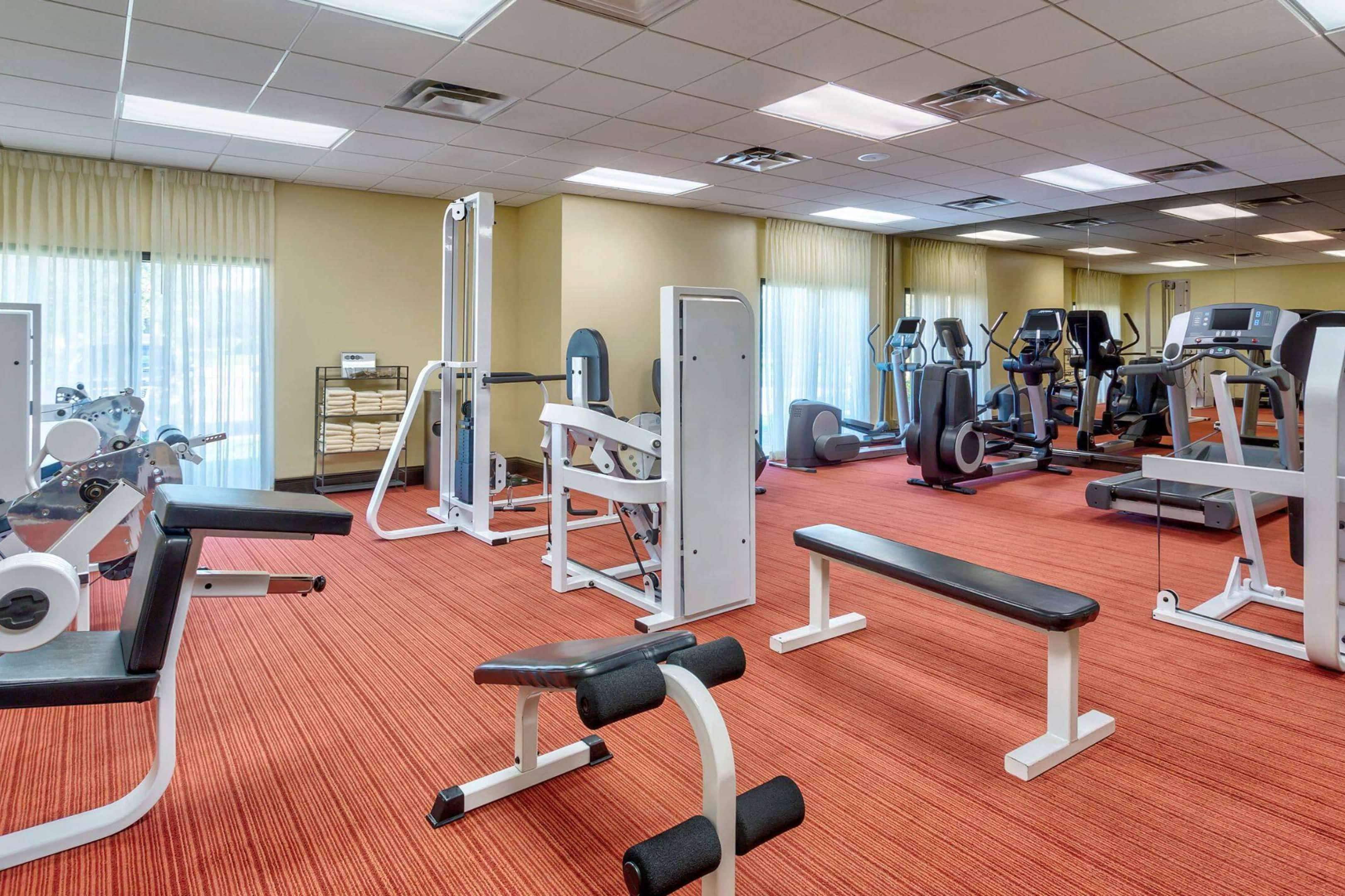 A gym with various exercise equipment, including treadmills, elliptical machines, and weight benches.