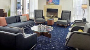 A modern living room with a sofa, two armchairs, a glass coffee table, and a fireplace. - Courtyard by Marriott Myrtle Beach Broadway (Myrtle Beach)