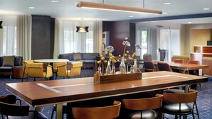 A hotel dining area with a long wooden table, multiple chairs, and a decorative centerpiece. - Courtyard by Marriott Myrtle Beach Broadway (Myrtle Beach)