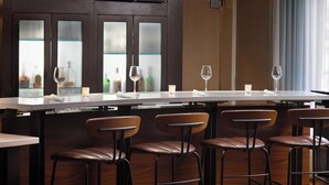 A bar area with a long counter, multiple stools, and a glass display case with bottles. - Courtyard by Marriott Myrtle Beach Broadway (Myrtle Beach)