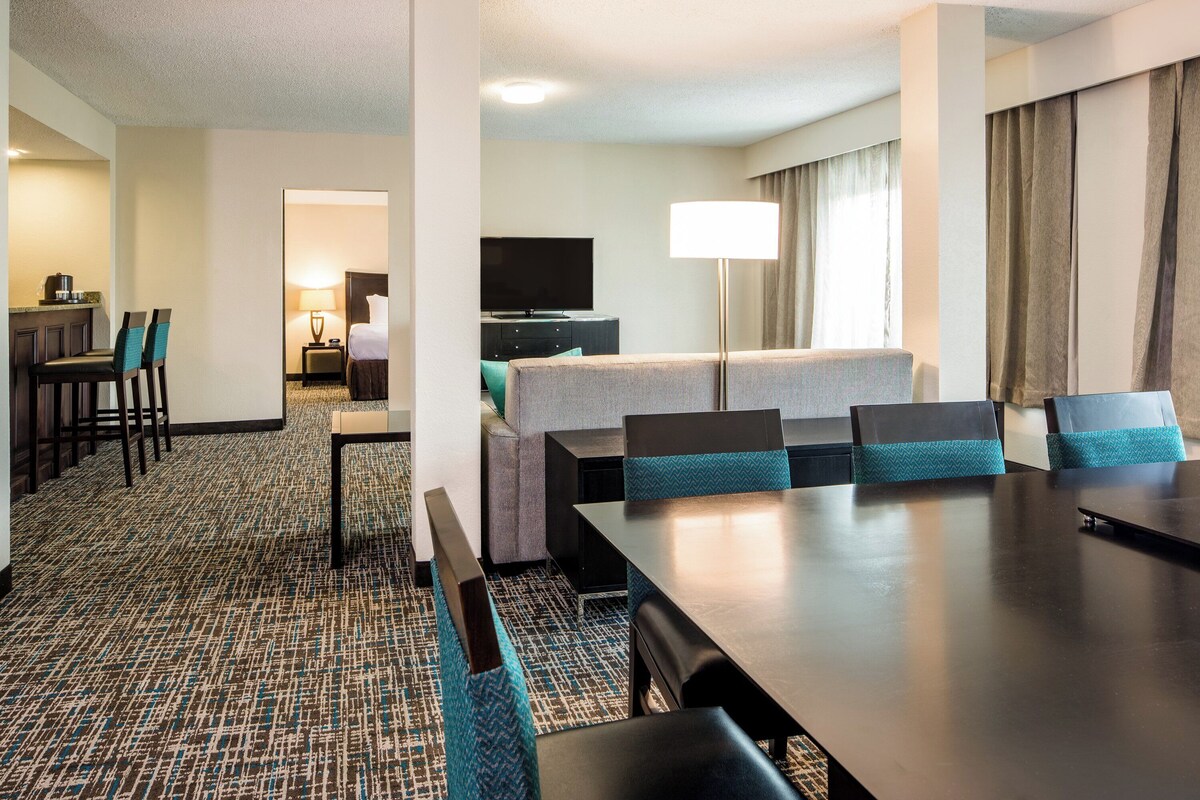 Une chambre d’hôtel comprenant un coin repas, un lit, une télévision et un bureau avec une lampe.