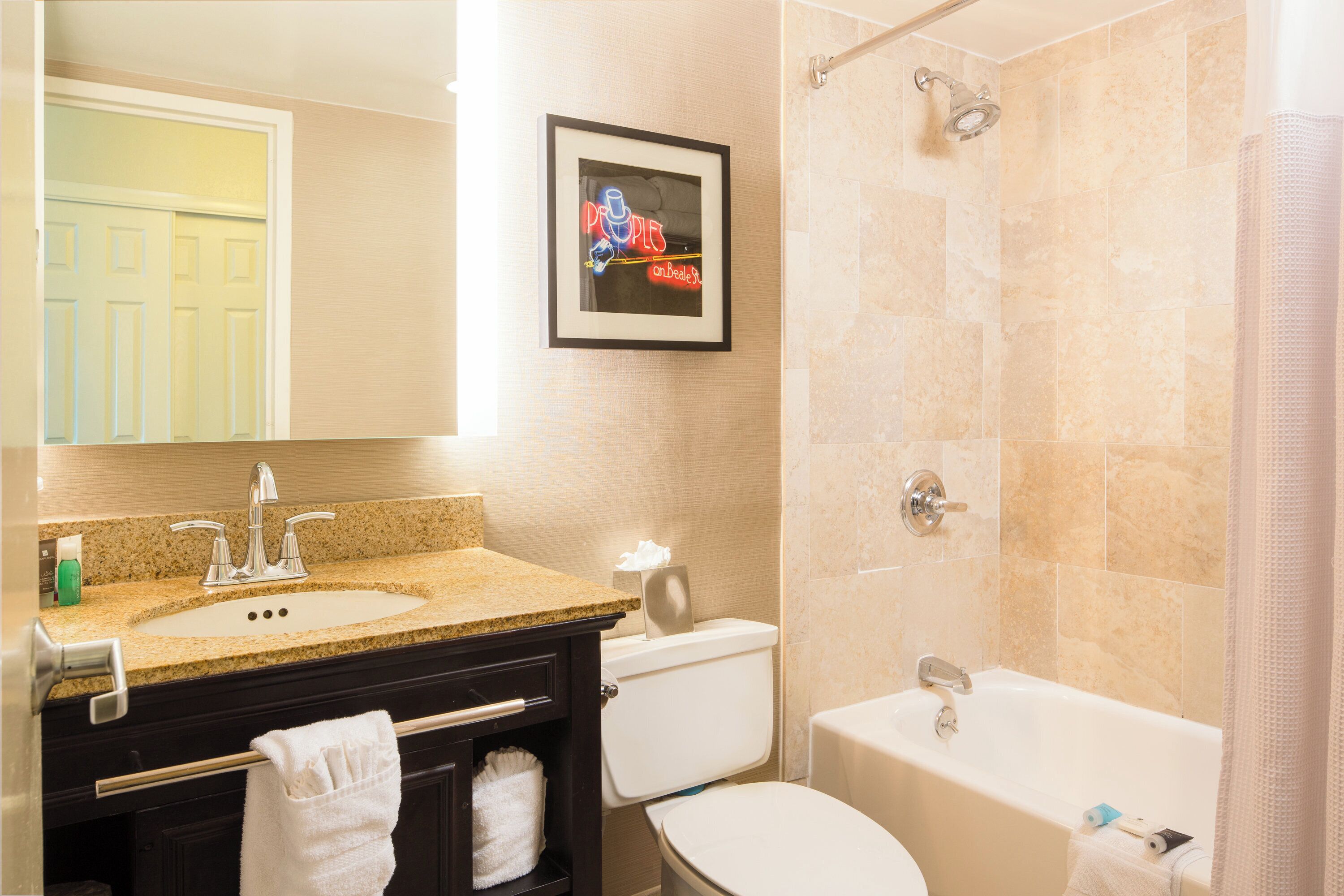 Une salle de bain avec un lavabo, des toilettes, une baignoire et un tableau encadré au mur.