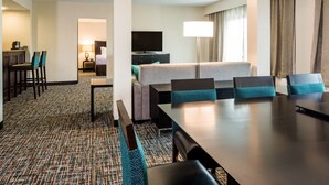 Une chambre d’hôtel comprenant un coin repas, une télévision, une lampe et un lit.