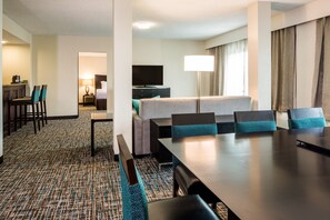 A hotel room with a dining area, a TV, a lamp, and a bed. - Crowne Plaza Memphis Downtown by IHG (Memphis)