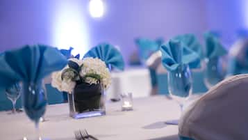 A table set with a vase of white flowers, a candle, and a fork.