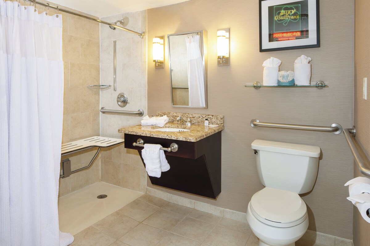 Une salle de bain équipée d’une douche, de toilettes, d’un lavabo et d’un panneau encadré accroché au mur.
