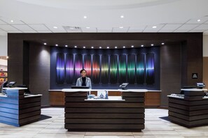 A reception area with a modern design, featuring a central desk with a computer and a digital display, flanked by two smaller counters. - Crowne Plaza Memphis Downtown by IHG (Memphis)