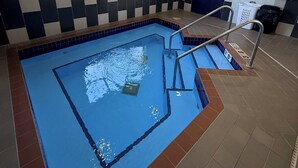 A swimming pool with a tiled border, a ladder, and a window with blinds. - Spark by Hilton Appleton (Appleton)